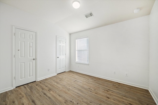 spare room with wood-type flooring and lofted ceiling