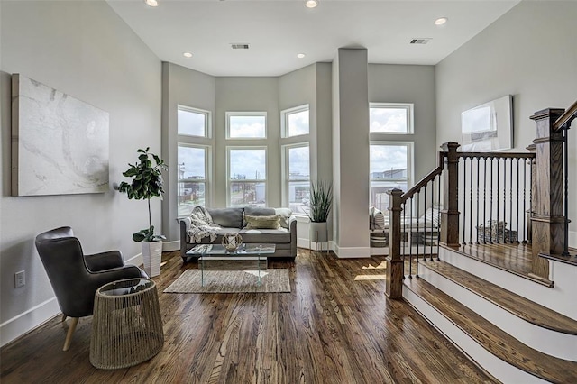 living area with a towering ceiling and dark hardwood / wood-style floors