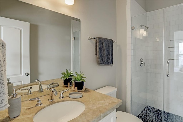 bathroom with vanity, toilet, and a shower with door