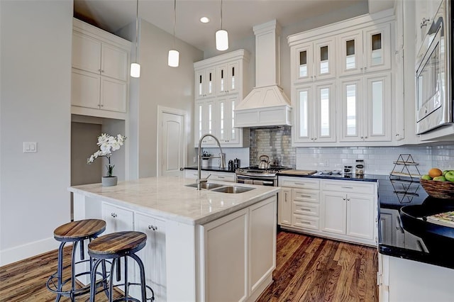 kitchen with appliances with stainless steel finishes, a kitchen island with sink, sink, pendant lighting, and white cabinetry