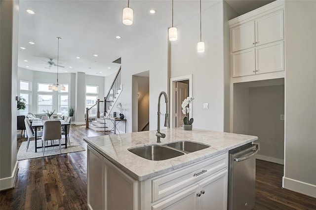 kitchen with a kitchen island with sink, sink, stainless steel dishwasher, dark hardwood / wood-style floors, and light stone countertops