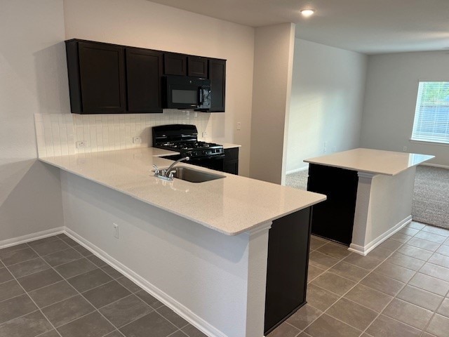 kitchen with black appliances, kitchen peninsula, sink, and dark tile patterned flooring