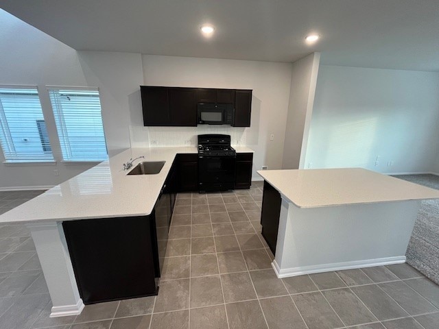 kitchen featuring black appliances, a kitchen island, kitchen peninsula, and sink