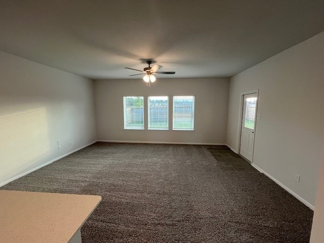 spare room featuring dark colored carpet, plenty of natural light, and ceiling fan