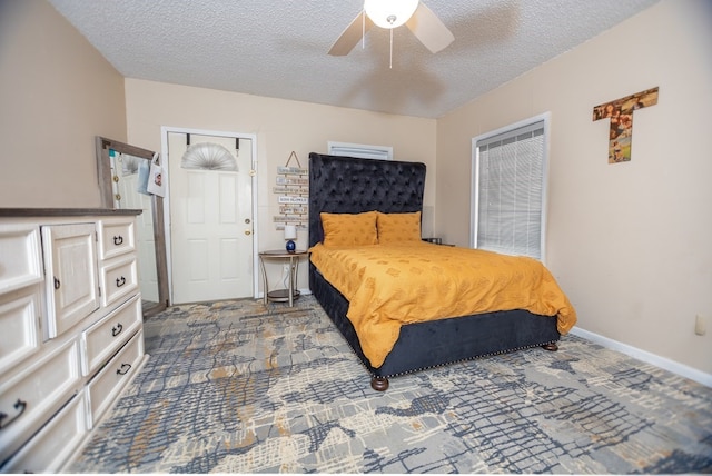 bedroom with ceiling fan, dark carpet, and a textured ceiling