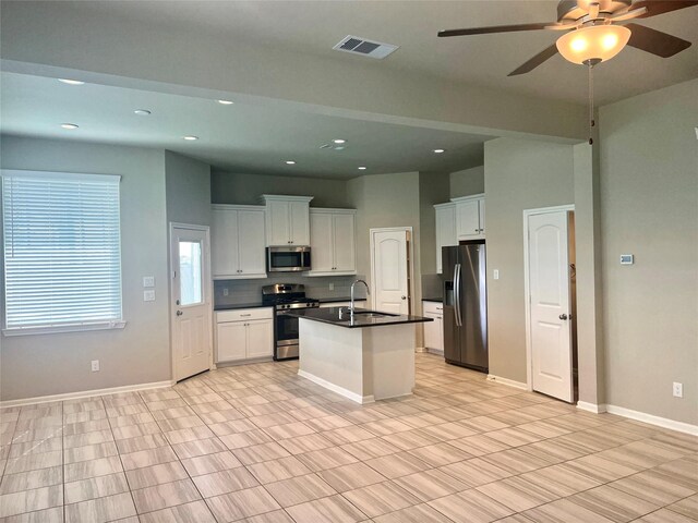 kitchen with white cabinetry, sink, ceiling fan, stainless steel appliances, and an island with sink