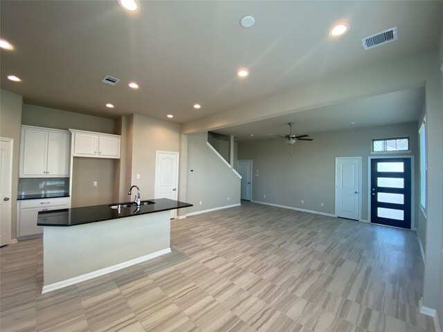 kitchen featuring ceiling fan, sink, white cabinets, and a center island with sink