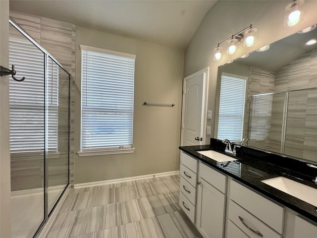 bathroom featuring vanity, a shower with shower door, and vaulted ceiling