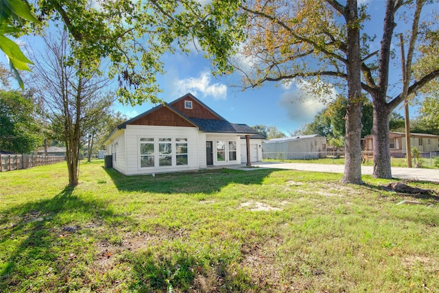 rear view of house featuring central AC and a lawn