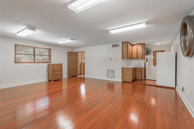 spare room with light hardwood / wood-style flooring, a textured ceiling, and sink