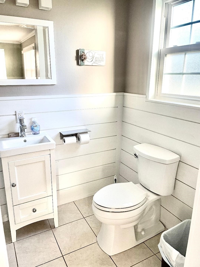 bathroom featuring tile patterned floors, wooden walls, vanity, and toilet