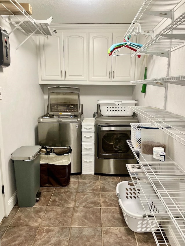 laundry area featuring dark tile patterned floors, cabinets, and independent washer and dryer