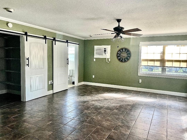 spare room featuring a barn door, ceiling fan, a textured ceiling, and ornamental molding