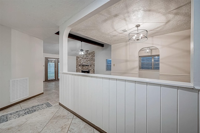 kitchen featuring a brick fireplace, a textured ceiling, vaulted ceiling with beams, hanging light fixtures, and light tile patterned flooring