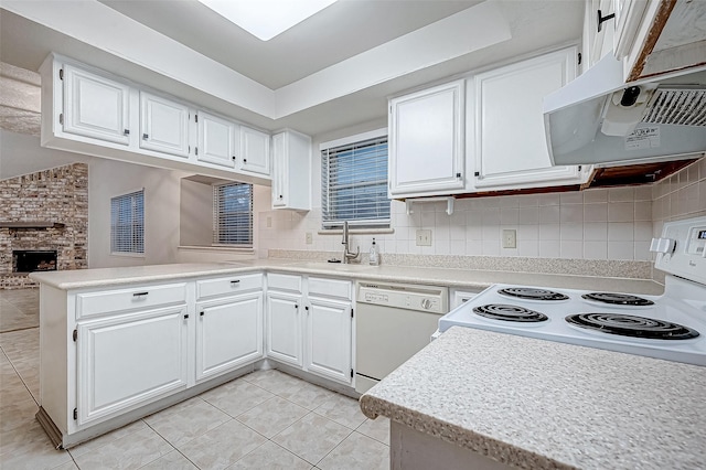 kitchen featuring white cabinets, kitchen peninsula, white appliances, a fireplace, and light tile patterned floors