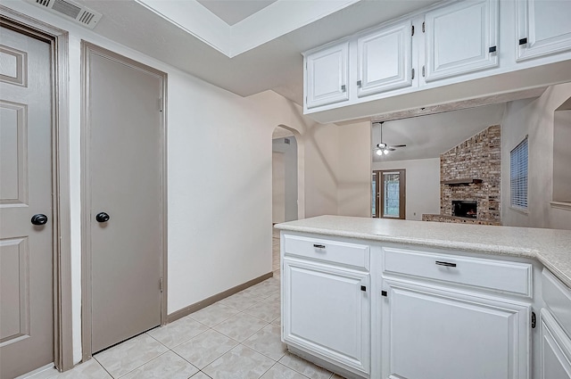 kitchen featuring white cabinetry, ceiling fan, lofted ceiling, a fireplace, and light tile patterned floors