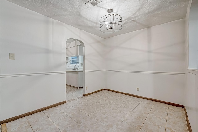 spare room with a textured ceiling, a notable chandelier, and sink