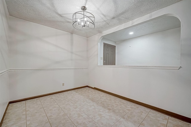 unfurnished room with a textured ceiling and a notable chandelier