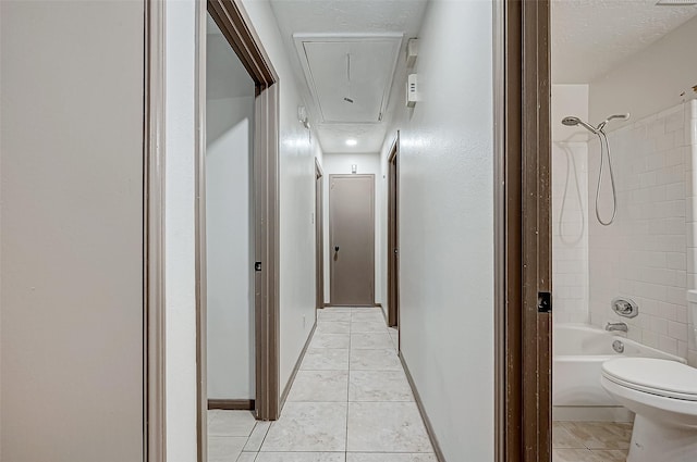 hall featuring light tile patterned floors and a textured ceiling