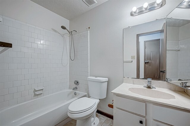 full bathroom featuring vanity, tile patterned floors, tiled shower / bath combo, toilet, and a textured ceiling