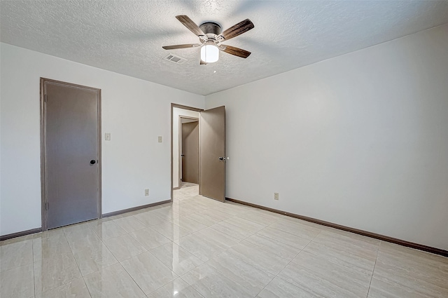 spare room with ceiling fan, light tile patterned flooring, and a textured ceiling