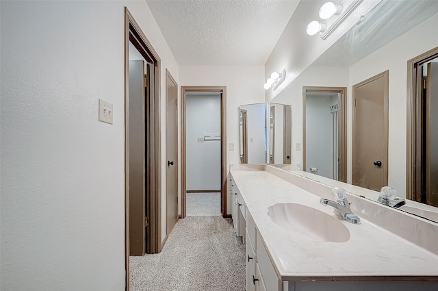 bathroom with tile patterned flooring, vanity, and a textured ceiling