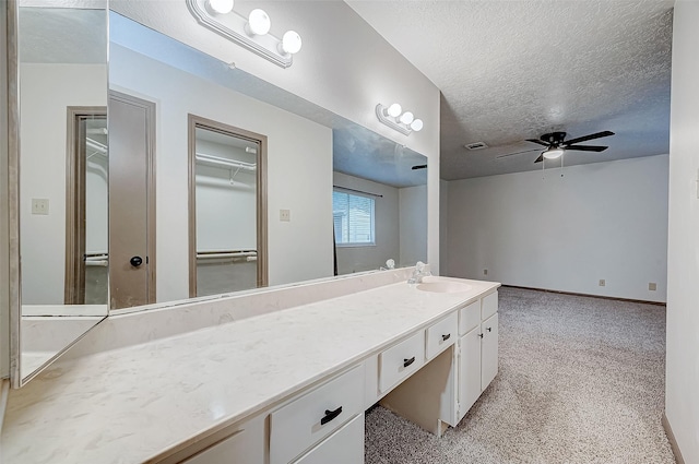 bathroom with ceiling fan, a textured ceiling, and vanity