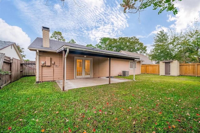 rear view of property featuring a yard, french doors, central air condition unit, a shed, and a patio