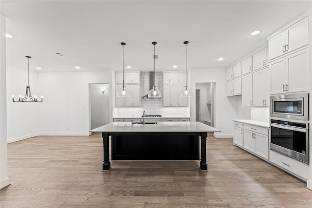 kitchen featuring white cabinets, appliances with stainless steel finishes, and an island with sink