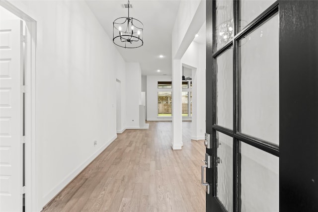 hall with light hardwood / wood-style flooring and an inviting chandelier