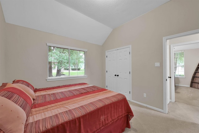 bedroom featuring lofted ceiling, light carpet, and a closet