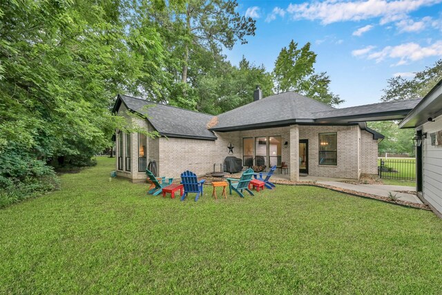 rear view of property with a fire pit, a yard, and a patio