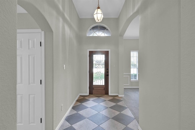 foyer entrance with a healthy amount of sunlight, crown molding, and light carpet