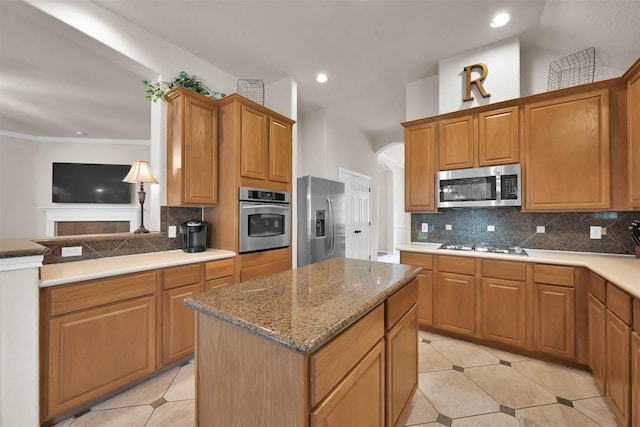 kitchen with appliances with stainless steel finishes, tasteful backsplash, a kitchen island, and light tile patterned flooring