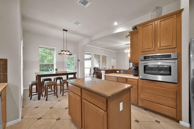 kitchen featuring stainless steel oven, ornamental molding, light tile patterned floors, decorative light fixtures, and a kitchen island