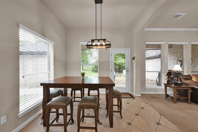 carpeted dining space featuring a chandelier, plenty of natural light, and ornamental molding