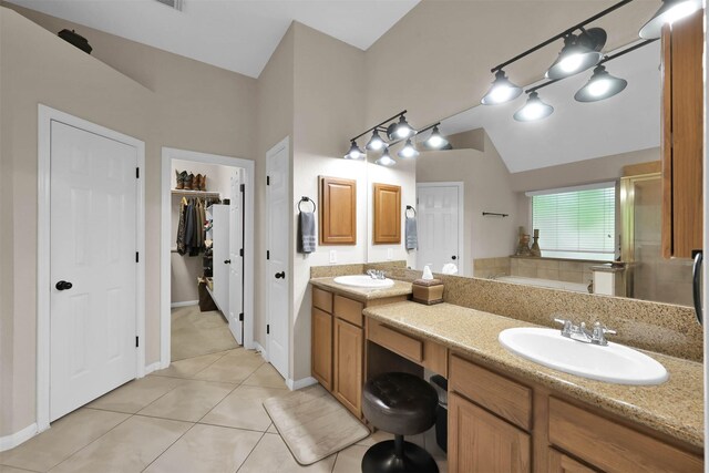 bathroom featuring vanity, a bath, vaulted ceiling, tile patterned flooring, and tasteful backsplash