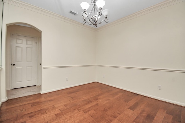 unfurnished room featuring hardwood / wood-style floors, ornamental molding, and an inviting chandelier