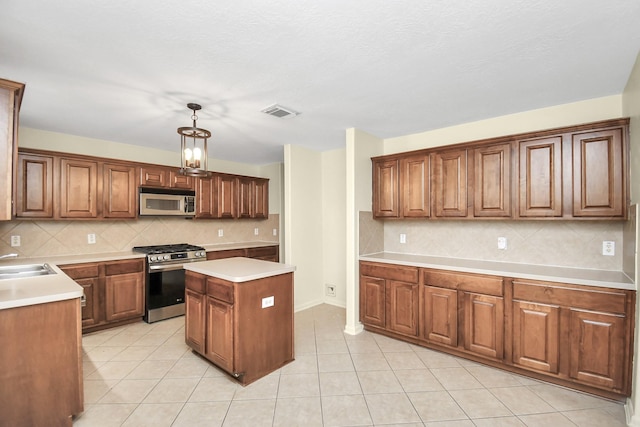 kitchen featuring decorative backsplash, appliances with stainless steel finishes, light tile patterned floors, a kitchen island, and hanging light fixtures