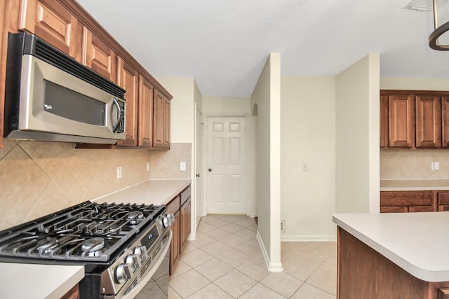 kitchen featuring light tile patterned flooring, appliances with stainless steel finishes, and tasteful backsplash