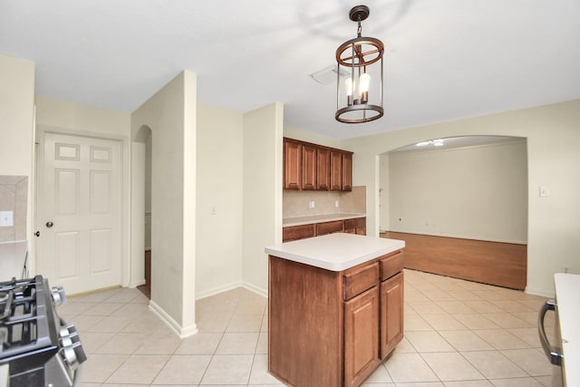 kitchen with backsplash, a center island, light tile patterned flooring, and stove