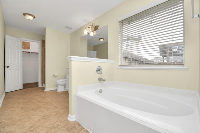 bathroom with tile patterned flooring, a bath, and toilet