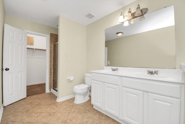 bathroom featuring tile patterned flooring, vanity, toilet, and a shower with door