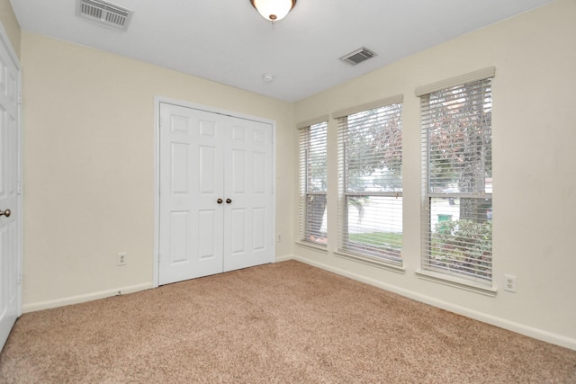 unfurnished bedroom with light carpet, multiple windows, and a closet