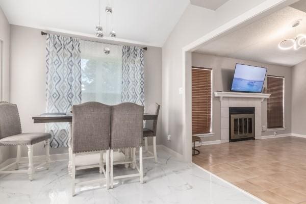 dining area featuring vaulted ceiling and a tiled fireplace