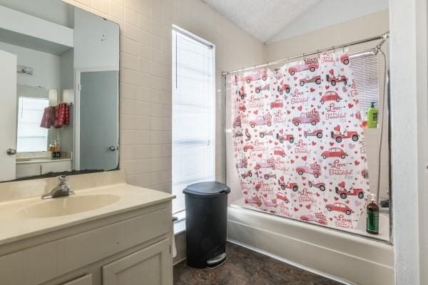 bathroom with tile walls, shower / tub combo with curtain, vanity, and lofted ceiling