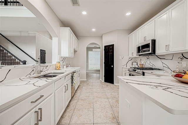 kitchen featuring sink, light tile patterned floors, decorative backsplash, white cabinets, and appliances with stainless steel finishes