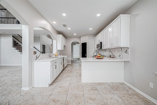 kitchen with white cabinets, light stone counters, kitchen peninsula, and light tile patterned floors