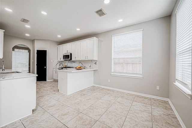 kitchen featuring kitchen peninsula, white cabinets, light tile patterned flooring, and sink