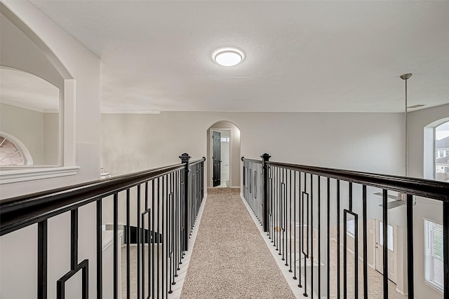 hallway featuring light colored carpet and a textured ceiling